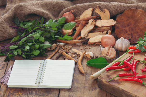 Vários ingredientes usados para fazer comida asiática são colocados junto com os cadernos na mesa de madeira. - Foto, Imagem