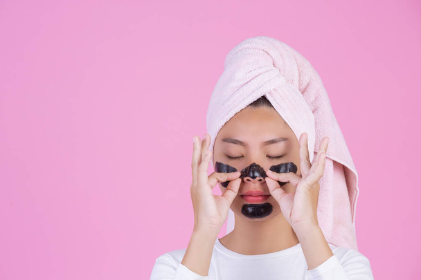 Beauty cosmetic peeling. Young female with black peel off mask on skin cosmetic skin care peeling product on face on a pink background. - Fotó, kép