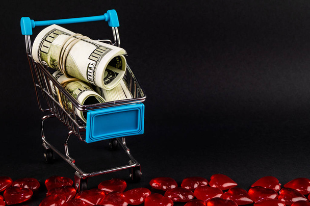 Supermarket trolley with money inside on dark background - Photo, image