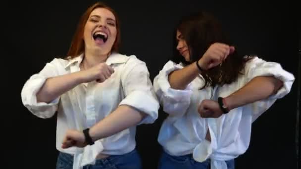 Tytöt valkoisissa paidoissa tanssivat ja pelleilevät mustalla taustalla
 - Materiaali, video