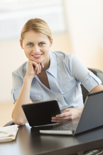 Бізнес-леді з рукою на Чін тримає цифровий планшет на столі
 - Фото, зображення