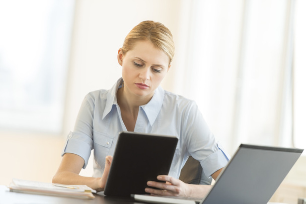 Businesswoman Using Digital Tablet While Sitting At Desk - Foto, immagini