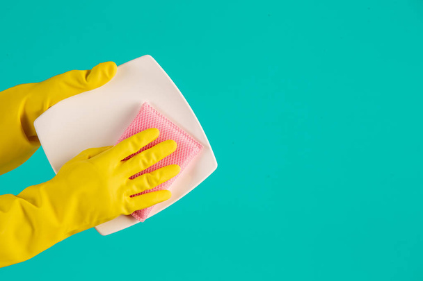 Le concept de lave-vaisselle portant des gants jaunes sur fond bleu. - Photo, image