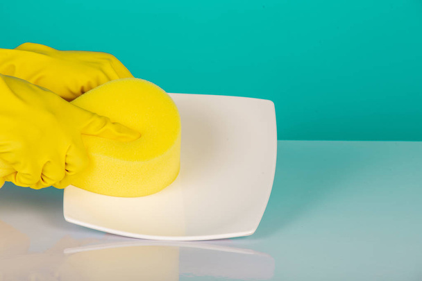 The concept of dishwasher wearing yellow gloves on a blue background. - Foto, afbeelding