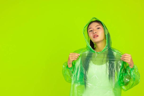 Girl is wearing a green rain dress on a green background. - Φωτογραφία, εικόνα