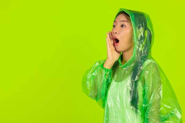 Girl is wearing a green rain dress on a green background. - Valokuva, kuva