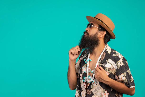 The concept of a happy man with a long beard wearing a hat, wearing a striped shirt showing a gesture on a blue background. - Fotó, kép