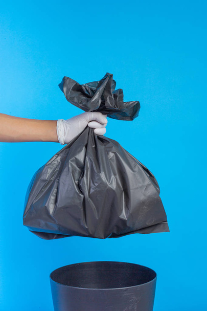 Die männliche Hand hält einen Müllsack und einen blauen Hintergrund. - Foto, Bild
