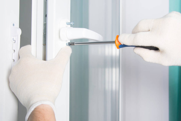 workers hands in protective gloves, screw the handle with a screwdriver to the plastic window - Fotoğraf, Görsel