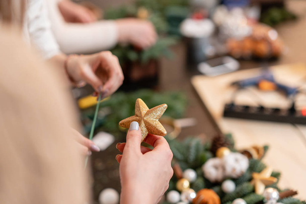 Una estrella en la mano de una mujer. La mujer creó un arreglo de Navidad. Clase magistral sobre la fabricación de ornamentos decorativos. Floristería
 - Foto, imagen