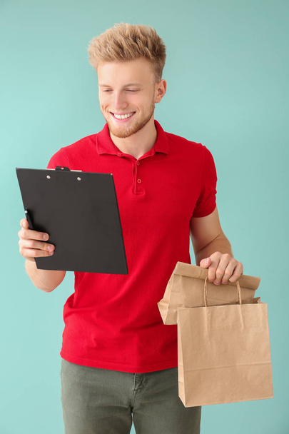 Handsome worker of food delivery service on color background - Photo, Image