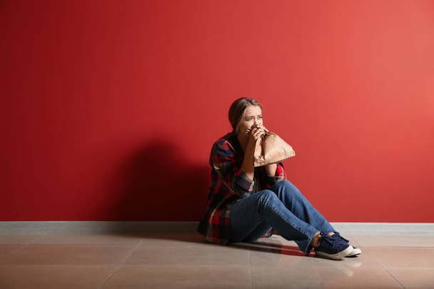 Kobieta o ataku paniki siedząc w pobliżu koloru ściany - Zdjęcie, obraz