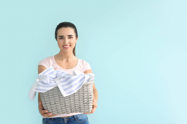 Beautiful young woman with laundry on color background - Фото, изображение