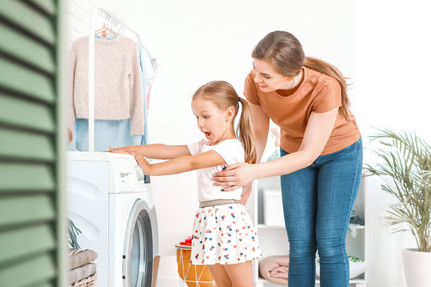 Femme et sa petite fille faisant la lessive à la maison
 - Photo, image