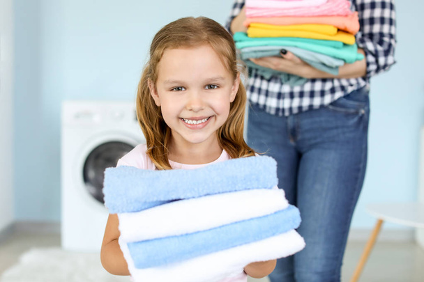 Woman and her little daughter with clean laundry at home - Foto, Imagem
