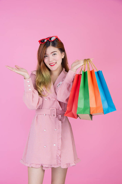 The girl holds a fashion shopping bag and beauty on a pink background. - Foto, Imagen
