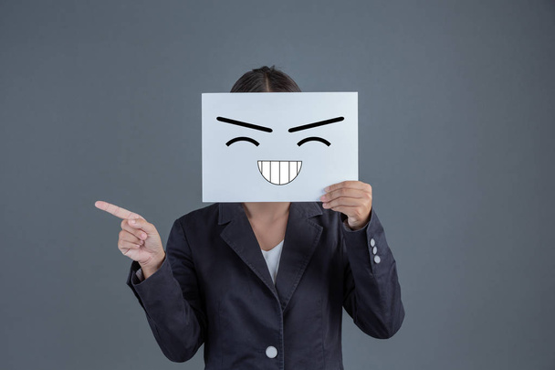 A businesswoman stood and made a gesture with a hard board, closing his face with a smiley face. - 写真・画像