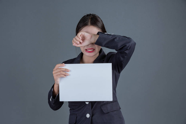 Office girl holding a white blank board on a gray background. - 写真・画像