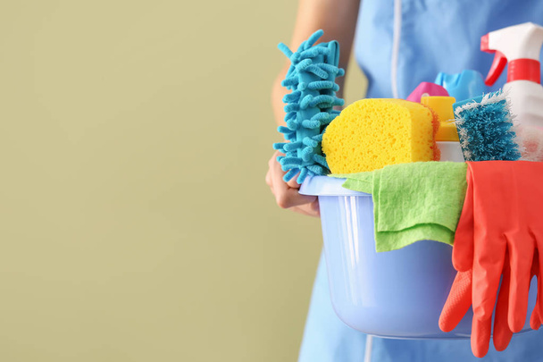 Female janitor with cleaning supplies on color background, closeup - Фото, изображение