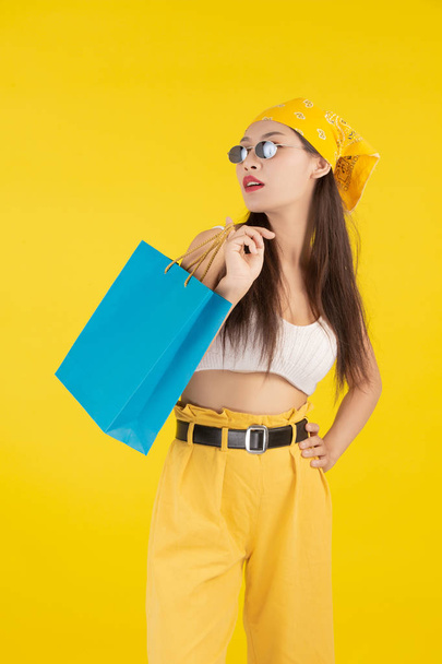 La fille tient un sac à provisions de mode et la beauté sur un fond jaune. - Photo, image