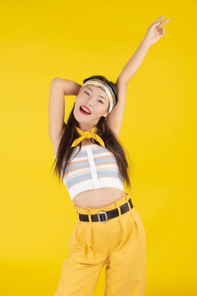 Fashion girl dress up with a hand gesture on a yellow background. - Zdjęcie, obraz