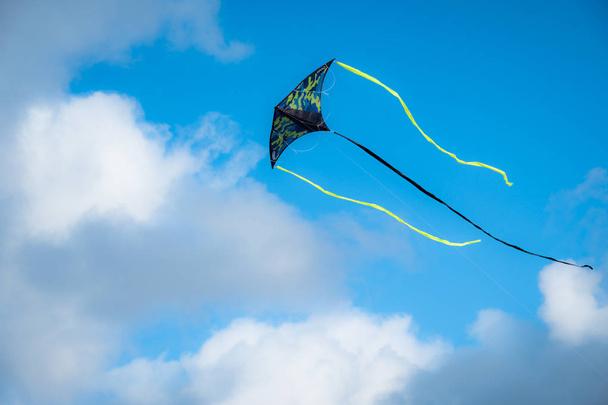 Drachen fliegen gegen den blauen Himmel. ein Spielzeug, das in der Luft fliegt, wenn es Wind ausgesetzt ist. Die Leitung erfolgt über Kabel. Sommer. Tag. - Foto, Bild
