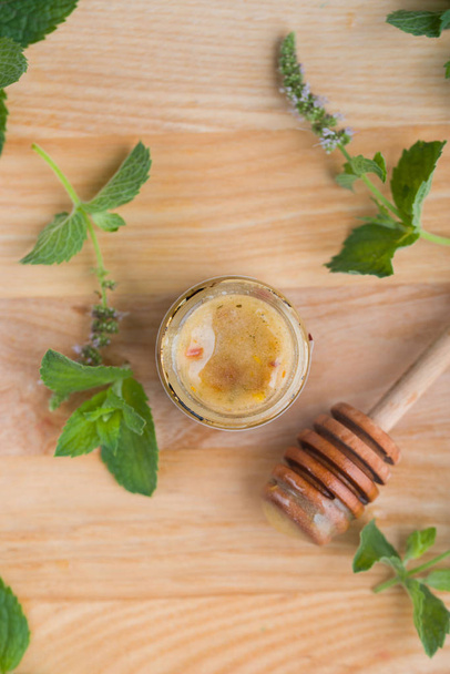 Tasty and aromatic honey in a jar with mint on a wooden table. - Fotó, kép