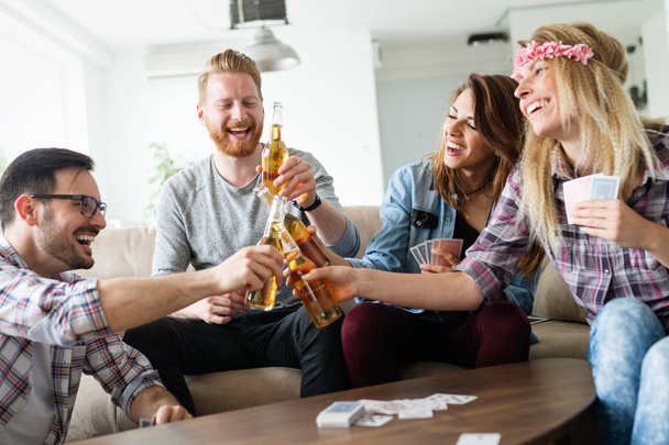 Happy group of friends playing cards and drinking - 写真・画像