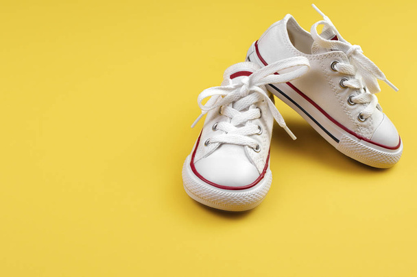 Photo of white sneakers over yellow background. - Fotografie, Obrázek