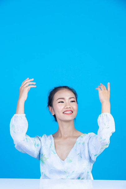 tiener meisje tonen hand werkwoorden en gebaren op een blauwe achtergrond. - Foto, afbeelding