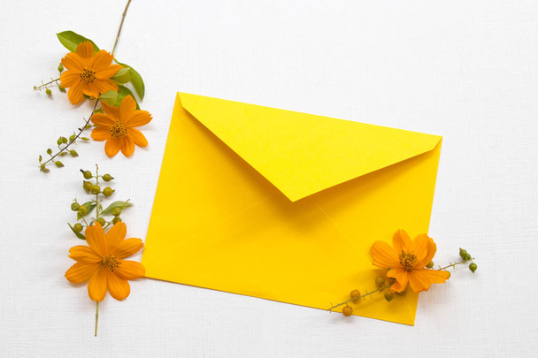 coloridas flores naranjas cosmos flora local de asia con arreglo de sobres amarillos estilo de postal laico plano sobre fondo madera blanca
 - Foto, Imagen