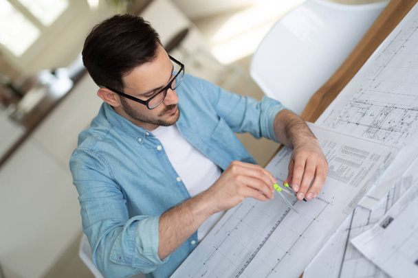 Portrait of adult architect working on plans and blueprints in office - Fotografie, Obrázek