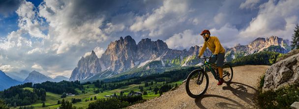 電動自転車でサイクリングする男性は、登山道に乗ります。乗る男 o - 写真・画像