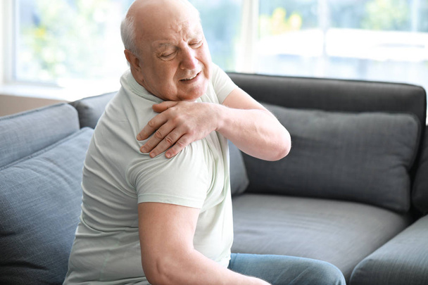 Старший мужчина страдает от боли в плече дома
 - Фото, изображение