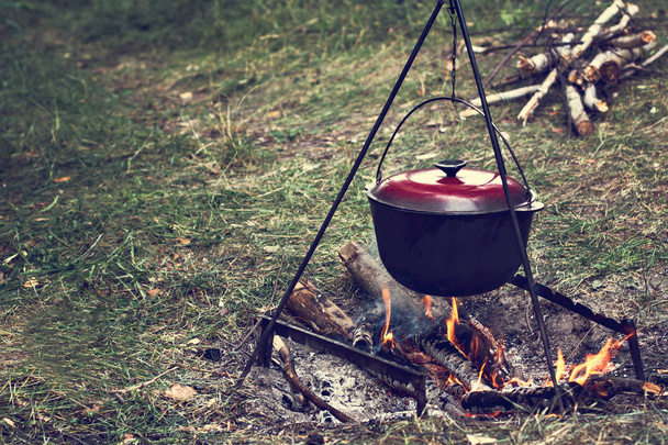 Een pot van vlees boven een vuur. Wandeling, zomervakantie, outdoor recreatie, buiten eten. Koken boven een kampvuur. toeristische ketel boven kampvuur. - Foto, afbeelding