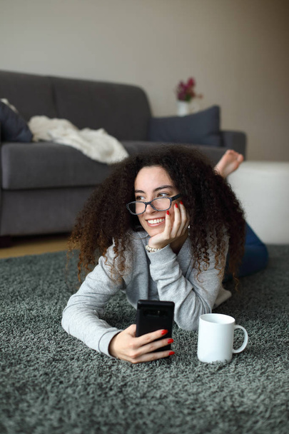 Relaxed casual girl texting on smartphone at home - Foto, afbeelding