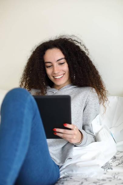 Casual girl reading on digital tablet in bed - Valokuva, kuva