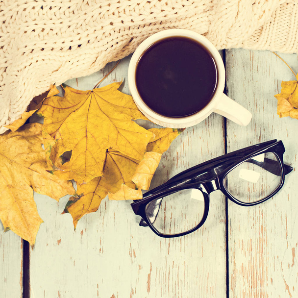 Chaud blanc tricoté plaid, café, téléphone, lunettes, feuilles d'automne sur un fond en bois
. - Photo, image