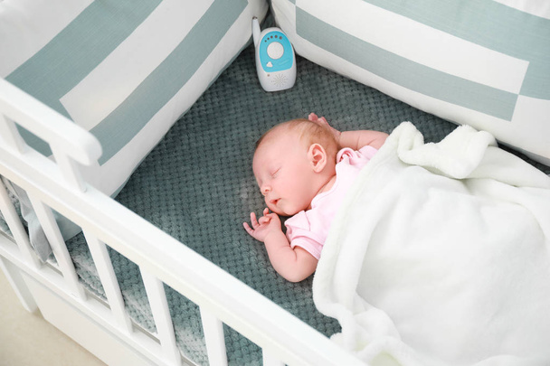 Schattige kleine baby met radio Nanny slapen in wieg - Foto, afbeelding