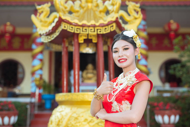 Güzel bir Asyalı kız kırmızı bir takım elbise giyiyor. Hareketlerini gösteriyor ve gülümsüyor. Onu mutlu gösteriyor.. - Fotoğraf, Görsel