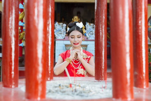 Een mooi Aziatisch meisje draagt een rode aanbidding g haar gebaren en glimlachen maakt haar kijken gelukkig. - Foto, afbeelding