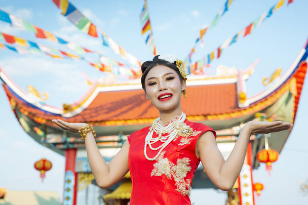 Una bella ragazza asiatica indossa un abito rosso mostrando i suoi gesti e sorridente la rende felice. - Foto, immagini