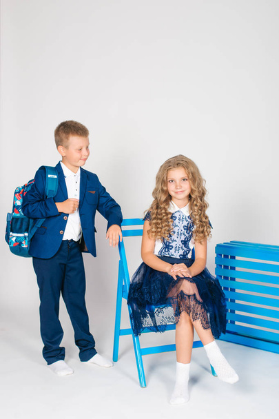 Boy and girl schoolchildren in fashionable school clothes with a school bag on a white background - Foto, imagen