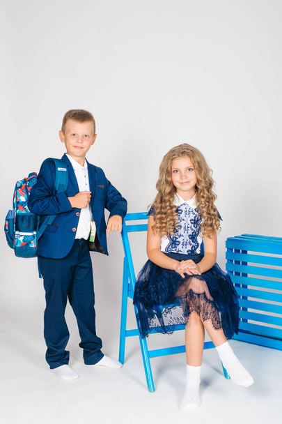 Boy and girl schoolchildren in fashionable school clothes with a school bag on a white background - Foto, afbeelding