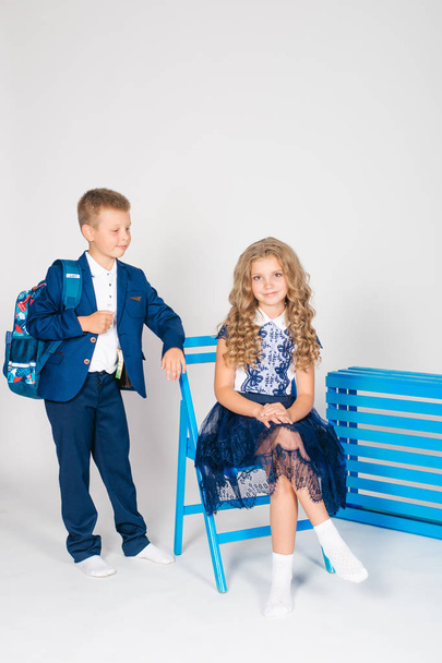 Boy and girl schoolchildren in fashionable school clothes with a school bag on a white background - Фото, зображення