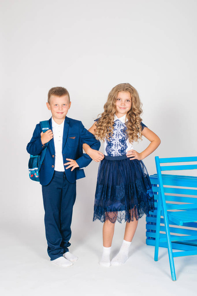Boy and girl schoolchildren in fashionable school clothes with a school bag on a white background - Foto, imagen