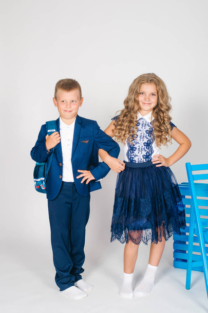 Boy and girl schoolchildren in fashionable school clothes with a school bag on a white background - Foto, Imagem