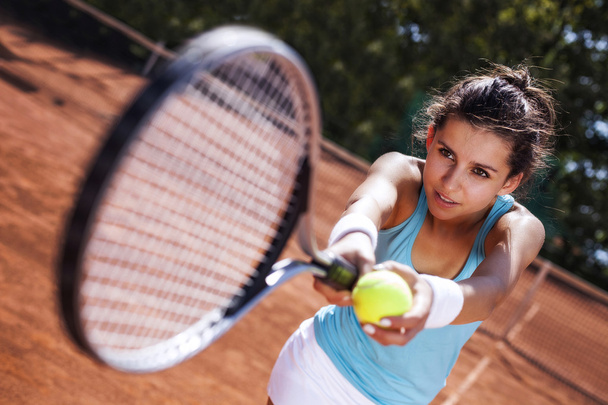 Young girl catching a ball in tennis court - Foto, afbeelding