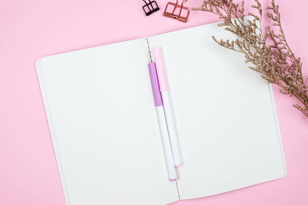 Bovenaanzicht van notebook briefpapier en bloem op roze achtergrond - Foto, afbeelding