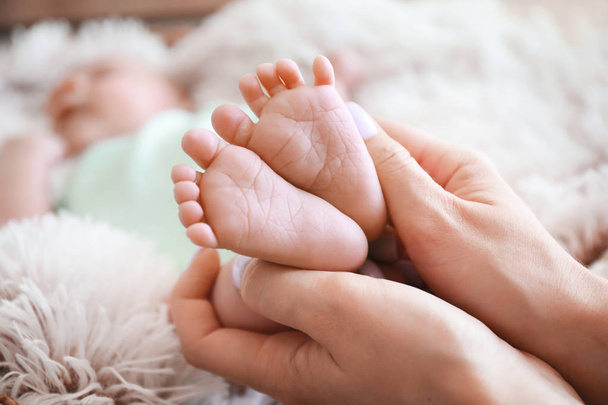 Mother's hands with tiny baby legs, closeup - Foto, afbeelding